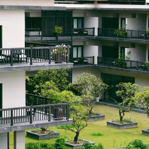 Contemporary multi-story building with lush courtyard and distinctive balconies, showcasing modern architecture.