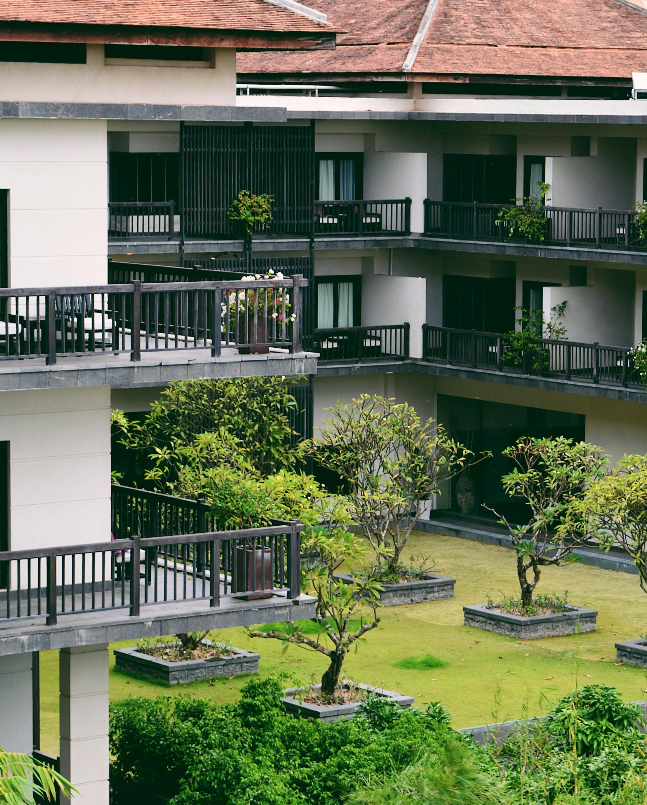pexels photo 8828076 8828076 Contemporary multi-story building with lush courtyard and distinctive balconies, showcasing modern architecture.